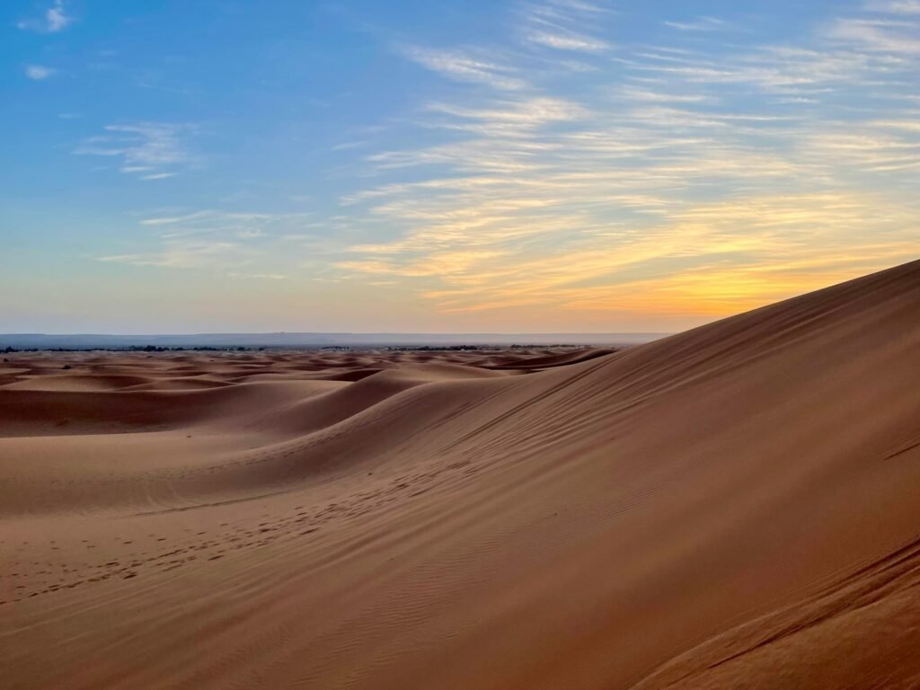 the sun is setting over the sand dunes