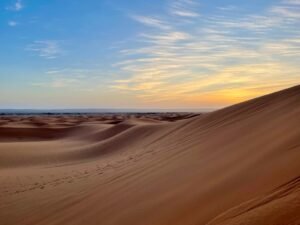 the sun is setting over the sand dunes